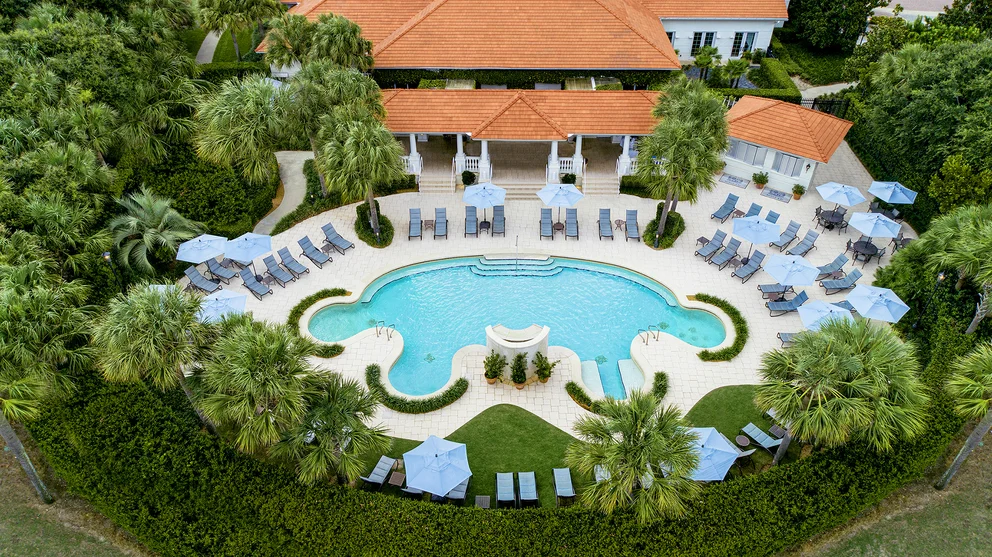 a swimming pool with lounge chairs and trees